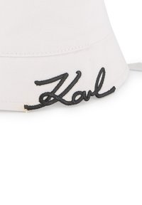 Witte bucket hat van stof, met een opvallend zwart geborduurd "Karl" logo aan de voorkant. Glad textuur met een gebogen rand.