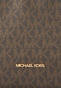 Brun textured taske med en guldfarvet logo. Designet inkluderer et subtilt mønster, der skaber dybde og dimension. Rektangulær form.