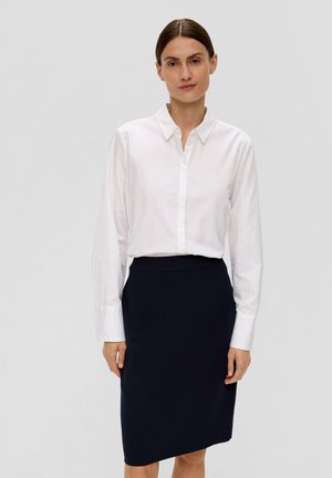 Witte blouse met lange mouwen, gecombineerd met een aansluitende marineblauwe kokerrok. Eenvoudig ontwerp, zachte textuur en klassieke kleuren.