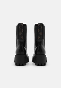 Botas negras de tobillo de cuero con paneles laterales elásticos y un acento estampado. Suela gruesa y texturizada con un diseño de tacón robusto.