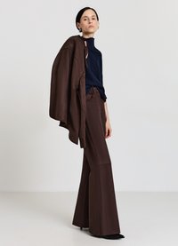 Braune weit geschnittene Hosen kombiniert mit einem navyblauen Strickoberteil, ergänzt durch eine braune Außenschicht, die glatte Texturen und schlichte Linien präsentiert.