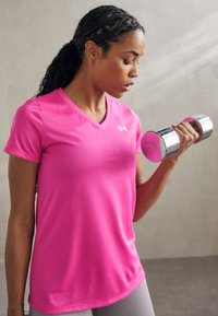 Roza majica kratkih rukava za sport s V-izrezom, u kombinaciji s srebrnim bučicama. Glatka tekstura, prilagođen stil s Under Armour logotipom.