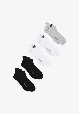 Tri par čarapa u crnoj, bijeloj i sivoj boji. Svaki par ima logo u području članaka i glatku, pamuk sličnu teksturu.