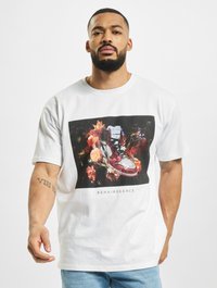 Tricou alb cu mânecă scurtă, având un grafic central cu flori și adidași roșii. Textul mare de dedesubt spune "RENAISSSANCE."