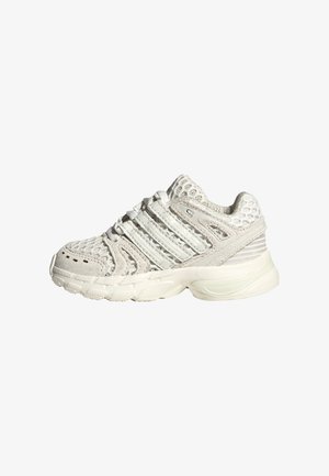 Witte atletische sneaker met mesh- en suède bovenlaag, dikke gewatteerde zool en meerdere gestikte strepen aan de zijkant, getoond in rechter profiel.