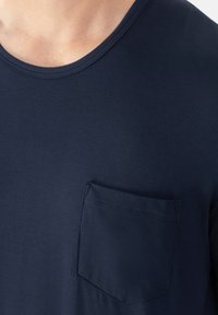 T-shirt in cotone blu navy con scollatura rotonda e maniche corte; presenta una singola tasca sul petto e una texture liscia e morbida.