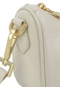 Borsa a mano in pelle crema con finitura testurizzata, dotata di hardware dorato e una chiusura elegante. Forma arrotondata con dettagli di cucitura sottili.