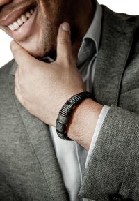 Schwarzes und silbernes geflochtenes Armband mit metallichen Akzenten, am Handgelenk getragen, das kontrastierende Texturen und Muster aufweist.