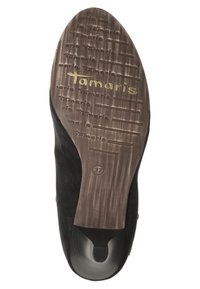 Suela de zapato de ante negro con una base de goma marrón texturizada que presenta un prominente logo dorado de "Tamaris" y la talla "37" grabada.