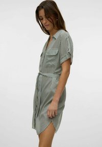 Abito camicia verde chiaro con righe verticali bianche, maniche corte, due tasche sul petto e una cintura in vita.