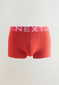 Červené bavlněné boxerky s růžovým elastickým pasem, na kterém je nápis "NEXT." Design je jednoduchý s prošitím a těsným střihem.