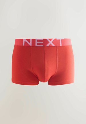 Boxer-briefs en coton rouge avec une ceinture élastique rose arborant le mot "NEXT". Le design est simple avec des détails de couture et une coupe ajustée.