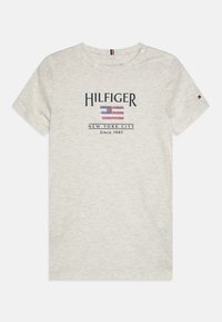 Svetlošedé tričko s krátkym rukávom a okrúhlym výstrihom, na ktorom je grafický dizajn loga Hilfiger a americká vlajka v strede.