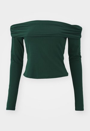 Zöld, vállon túl hosszú ujjú blúz. Simább anyagból készült, a vállakon gyűrt részletekkel, testhez álló fazonnal és rövidített hosszal.