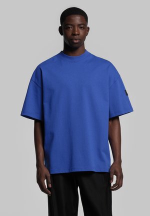 Blue oversized short-sleeve T-shirt made from soft cotton, featuring a ribbed crew neckline and a small black label on the left sleeve.