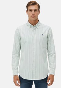 Camisa de manga larga a rayas verde claro y blanca con cuello abotonado, con un pequeño logo azul en el pecho y cierres de botones.