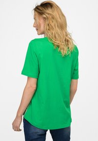 Grøn t-shirt med korte ærmer og rundet kant, lavet af blødt bomuldsstof. Har en afslappet pasform og sideskår for ekstra komfort.