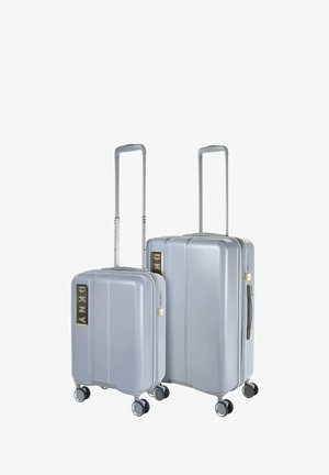 Dos maletas rígidas en gris claro, con detalles del logotipo dorado de DKNY, asas retráctiles y ruedas de 360 grados para una fácil maniobrabilidad.