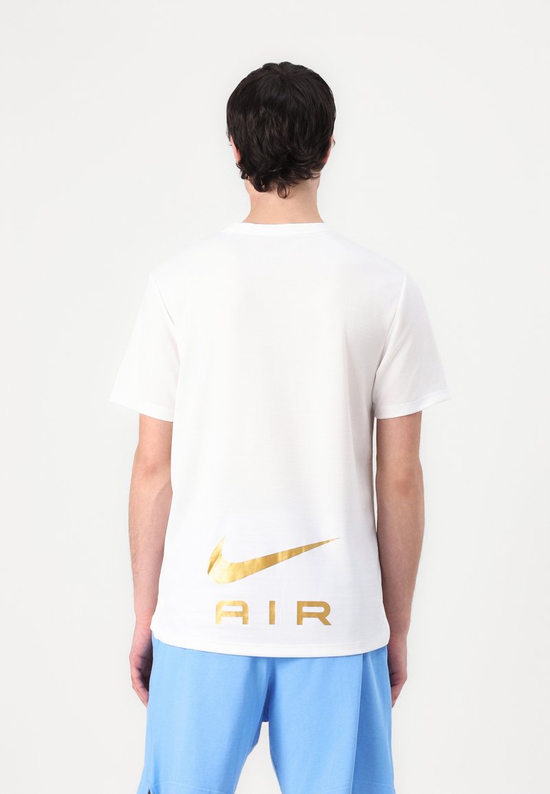 Balta medvilnė marškinėliai trumpomis rankovėmis, su dideliu auksiniu Nike logotipu ir "AIR" spauda ant nugaros. Lygus paviršiukas.