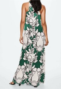 Robe longue avec un fond vert orné de grands motifs floraux blancs aux contours noirs. Fabriquée en tissu léger avec une coupe ample.