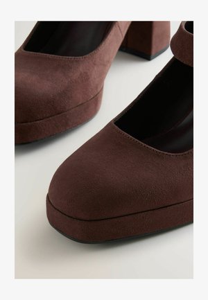 Bruine leren hoge hakken met een ronde neus, stevige hak en een veilige enkelband, met een gladde textuur en minimalistisch ontwerp.