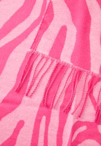 Plaid rosa zebra con frange ai bordi, texture morbida e tonalità di rosa che variano in schemi audaci e ampi.