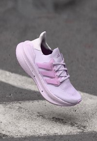 Purple athletic shoe featuring a mesh upper, thick midsole, and three-stripe design in contrasting pink. Lightweight and breathable construction.