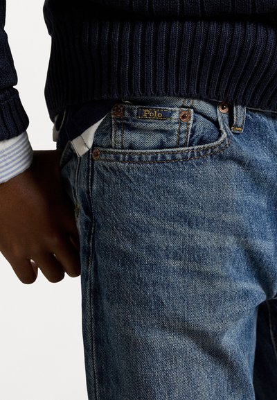 Džínsy v strednom modrom praní s klasickým strihom, s kontrastným prešívaním, dizajnom s piatimi vreckami a jemnou značkovou nálepkou na opasku.