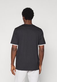 Μαύρο t-shirt με στρογγυλή λαιμόκοψη και κοντά μανίκια, με λευκές λεπτομέρειες στις μανσέτες. Κατασκευασμένο από βαμβακερό ύφασμα με απαλή υφή.