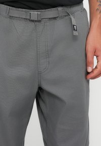 Gray pants made of lightweight fabric with an adjustable belt. Features include a smooth texture, stitching details, and side pockets.