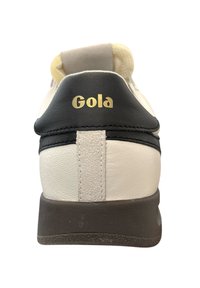 Weiße Leder Sneakers mit schwarzen Akzenten und beigem Fersenbereich. Der Anhänger zeichnet ein auffälliges goldenes "Gola"-Logo aus. Strukturierte Sohle und kontrastierende Nähte.