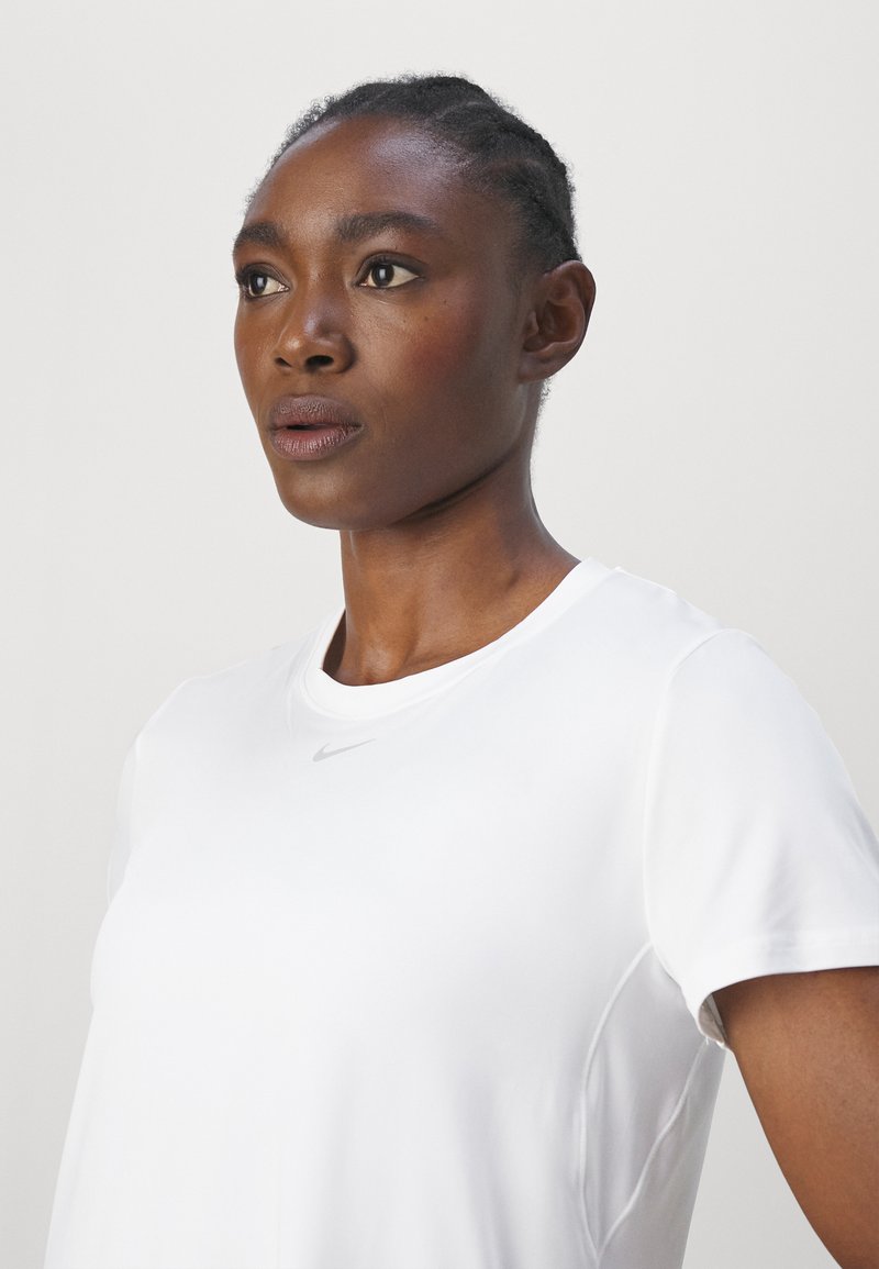 Weißes Sportshirt mit kurzen Ärmeln und rundem Ausschnitt sowie einem kleinen silbernen Nike-Logo auf der oberen linken Brust. Glatte Textur, leichtes Material.