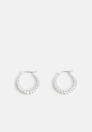 Paire de boucles d’oreilles créoles en argent avec un design texturé et torsadé et des fermoirs à charnières sur fond blanc uni.
