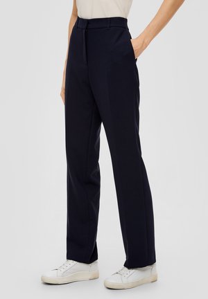 Navyblauwe, op maat gemaakte broek met een rechte snit, voorzien van een gladde textuur, zijzakken en een hoge taille. Gecombineerd met witte sneakers.