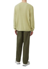 Hellgrüner, gerippter Pullover mit Rundhalsausschnitt, kombiniert mit olivgrünen Hosen. Bemerkenswerte Details sind der lockere Schnitt und die langen Ärmel.