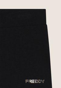 Pantaloni della tuta neri con vita a costine e logo "FREDDY" in metallo argentato. Il tessuto ha una texture liscia.