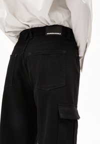 Schwarze Baumwoll-Cargo-Hosen mit Gesäßtaschen und einem Patch-Label. Das Design verfügt über gerade Beine und eine Gürtelschlaufe zur Anpassung der Passform.