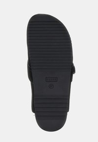 Semelle noire avec des rainures horizontales, arborant en relief de manière proéminente le nom de la marque "GUESS" et la taille "37". Bords en matériau doux et texturé.