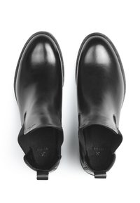 Bottines noires en cuir avec une finition lisse, des côtés découpés et de petites languettes à l'arrière. Elles disposent d'une semelle intérieure texturée.