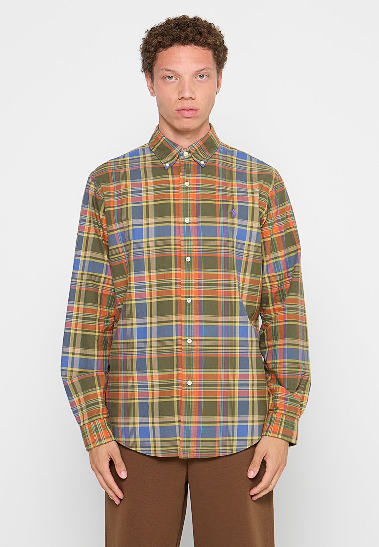 Chemise à manches longues en carreaux présentant un mélange de couleurs vert, orange, bleu et jaune. Col boutonné avec un petit logo sur la poitrine.