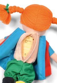 Pop met oranje gevlochten haar, gekleed in een blauw en rode outfit. Achterzak onthult een gele elektronische component binnen een zacht stoffen lichaam.