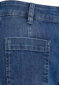 Jeans din denim albastru închis cu o textură netedă, având o buzunare din spate cu detalii vizibile de cusătură și un talie standard.