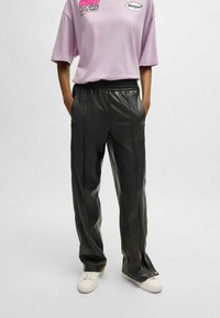 Zwarte faux leren broek met een relaxte pasvorm, voorzien van een elastische tailleband en voornaad, gecombineerd met een kortetermijn lavendel t-shirt.