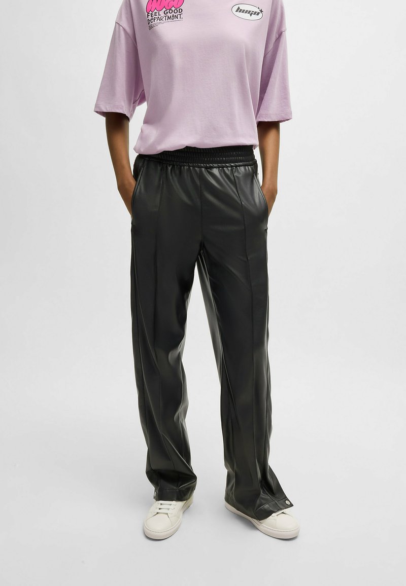 Zwarte faux leren broek met een relaxte pasvorm, voorzien van een elastische tailleband en voornaad, gecombineerd met een kortetermijn lavendel t-shirt.
