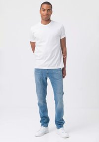 T-shirt bianca in cotone e jeans in denim azzurro chiaro. Fit slim con taglio dritto, abbinati a sneakers bianche. Design semplice e minimo dettaglio.