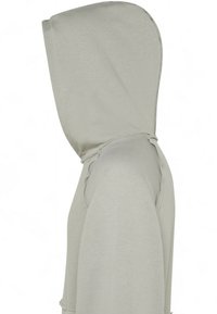 Felpa con cappuccio grigio chiaro dalla texture liscia, vista laterale che mette in risalto la forma del cappuccio e i dettagli cuciti.