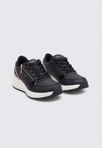 Sneakers neri con una texture liscia, dotati di una cerniera laterale, suola intermedia bianca e sottili accenti metallici per un contrasto. Progettati per il comfort.