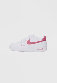 Valkoiset Nike Air Force 1 -tennarit, joissa on vaaleanpunainen Swoosh ja aksentti kantapäässä. Piirteet perforoitu varvasosa ja kumipohja.