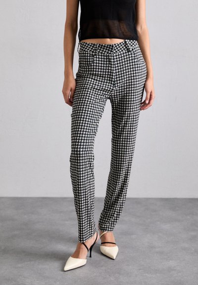 Spodnie w czarno-białą kratę houndstooth wykonane z lekkiego materiału, dopasowane, z średnim stanem i przednimi kieszeniami.