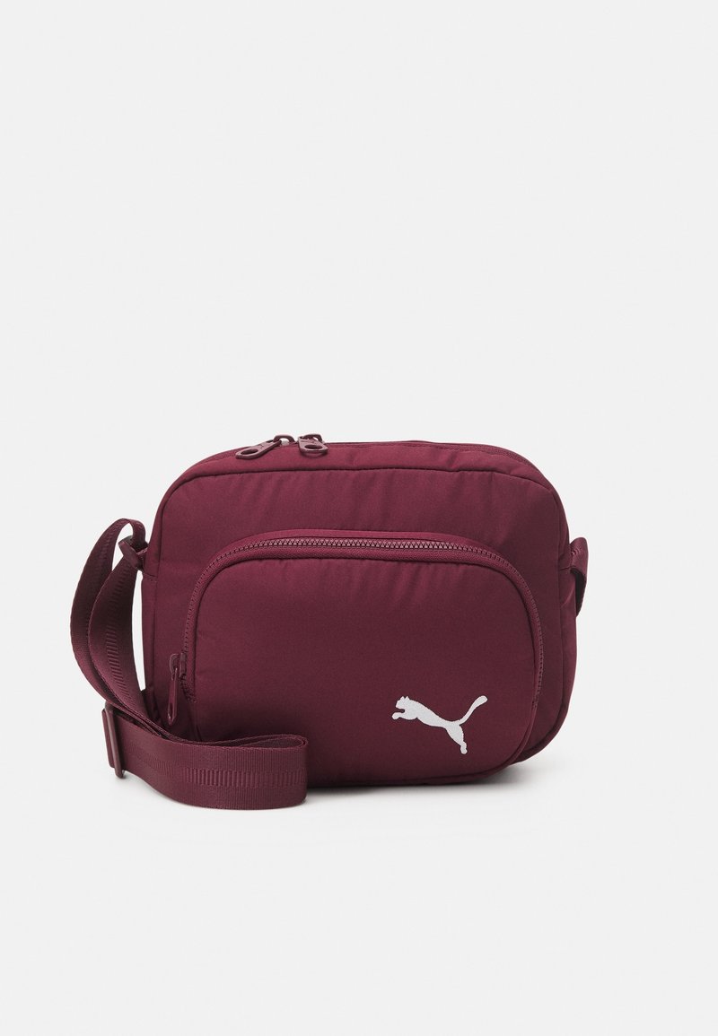 Bordeaux skuldertaske med glat overflade, lynlåslukning og justerbar rem. Har et hvidt Puma-logo på frontlommen.